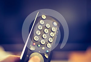 Male hand is holding TV remote control, smart TV