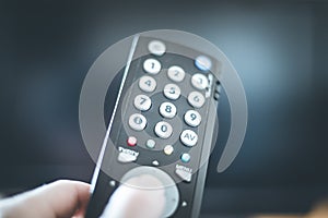 Male hand is holding TV remote control, smart TV