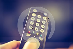 Male hand is holding TV remote control, smart TV