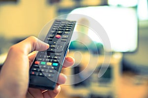 Male hand is holding TV remote control, smart TV