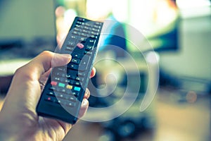 Male hand is holding TV remote control, smart TV