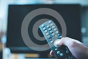 Male hand is holding TV remote control, streaming on a smart TV