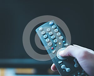 Male hand is holding TV remote control, streaming on a smart TV