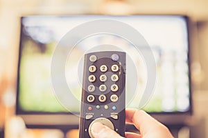 Male hand is holding TV remote control, streaming on a smart TV