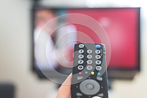 Male hand is holding TV remote control, streaming on a smart TV