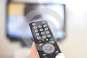 Male hand is holding TV remote control, streaming on a smart TV