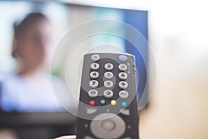 Male hand is holding TV remote control, streaming on a smart TV