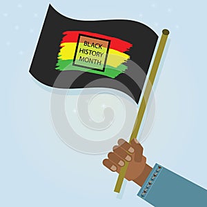 Male hand holding and waving Black History Month flag on blue gradient background
