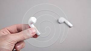 Male hand holding white wireless earphones