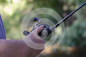 The male hand holds the baitcasting reel photo