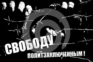 Male hand holds barbed wire in the dark with a russian writing: Freedom for political prisoners