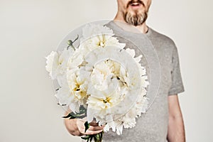 Male hand holds beautiful bouquet of white peonies. Flower delivery, gift, romantic concept