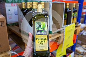 a male hand holds a bottle of olive oil in a large supermarket.