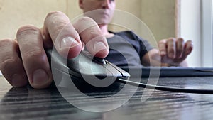 A male hand holds a computer mouse. Computer mouse close-up, fingers clicking