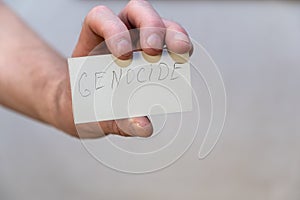 Male hand holds paper with word Genocide on it. Genocide is the intentional destruction of a people - usually defined as an ethnic