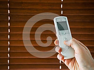 male hand holds a remote control to open the window blinds