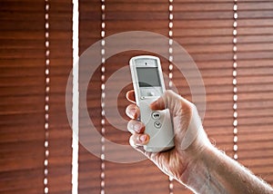 male hand holds a remote control to open the window blinds