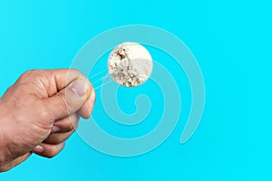 Male hand holds a scoop with protein on blue background top view.