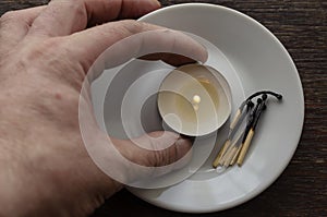 A male hand holds a small burning candle