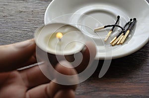 A male hand holds a small burning candle