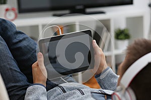 Male hand holds tablet in home setting while