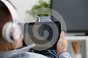 Male hand holds tablet in home setting while