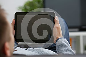 Male hand holds tablet in home setting while