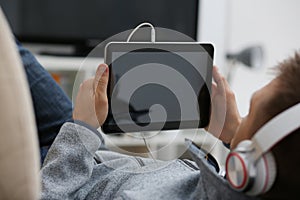 Male hand holds tablet in home setting while