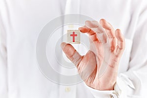 Male hand holds a wooden cube with the religious cross symbol. Christianity belief or religion