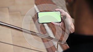 Male hand horizontal keeping touch screen smart phone urban city mock up tapping display green screen chromakey outside