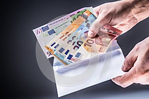 Male hand inserted into the envelope euro banknotes - bribe and corruption concept