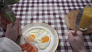 Male hand knocking on the table with his fists with fork and knife, demanding food. Plate with fried eggs appearing on