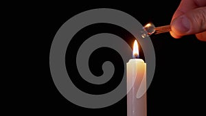 Male Hand Lights Two Matches on a Black Background from a Burning Candle. 4K