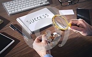 Male hand magnifying coins. Inspect income