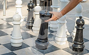 Man playing big chess outdoors. Male hand making a move while playing big chess game on the ground. . Strategy or decision concept
