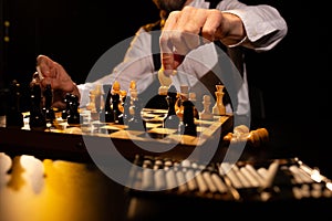 Male hand making move by white knight on chessboard in dark room