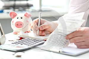 Male hand making some notes with silver pen on paper about cash flow