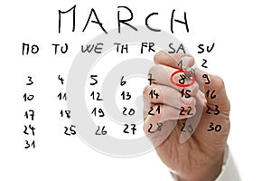 Male hand marking on calendar the date of March 8