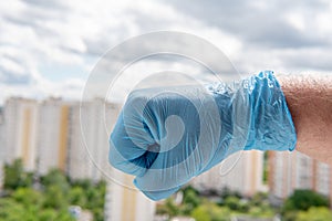 Male hand in a medical glove clenched into a fist against a cityscape