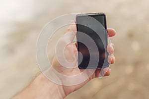 Male hand with mobile phone on the beach