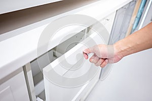 Male hand opening drawer on white cabinet