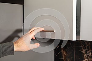 Male hand opening kitchen cupboard door
