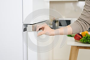 Male hand is opening white refrigerator door