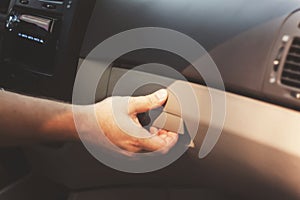 Male hand opens the glove compartment in the car, retro toning