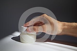 Male hand opens White plastic tube with round cap on white background with shadows. Front view for your design. facial cosmetic pr