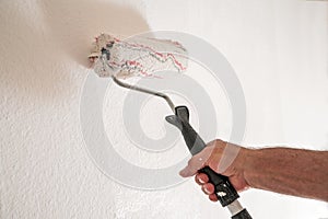 Male hand with paint roller painting the walls, renovation concept when moving to a new apartment, real estate concept, copy space