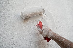 Male hand painting wall with white paint roller