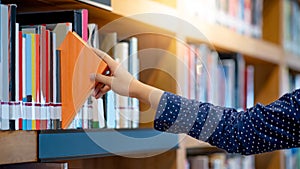 Male hand picking book in library