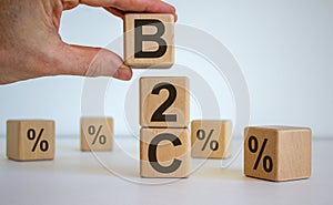 Male hand placing a cube with letter B on top of a other cubes. B2C text. Beautiful white background