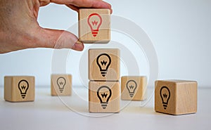 Male hand placing a cube with light bulb icon on top of a other cubes. The concept of finding an idea. Beautiful white background